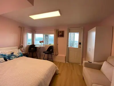 a bedroom with a bed and a couch and a table at Beachbreeze Panoramic Oceanview 5BR 4BA Romantic Sunrise & Celestial Views in Mill Bay