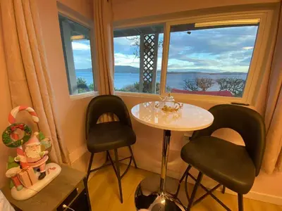 a small table and two chairs in a room with a window at Beachbreeze Panoramic Oceanview 5BR 4BA Romantic Sunrise & Celestial Views in Mill Bay