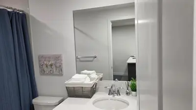 a bathroom with a sink and a toilet and a mirror at Modern 2BR near Hospital, YMCA, Stores in Calgary