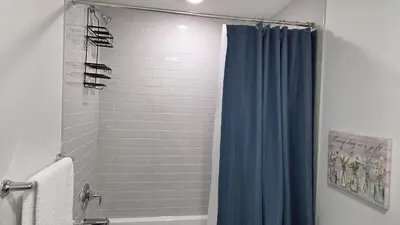 a bathroom with a shower with a blue shower curtain at Modern 2BR near Hospital, YMCA, Stores in Calgary