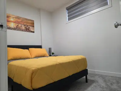 a bedroom with a bed with yellow sheets and a window at Modern 2BR near Hospital, YMCA, Stores in Calgary