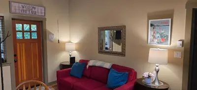 a living room with a red couch and a mirror at A Shack In The Woods in Port Renfrew