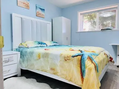 a bedroom with a bed with blue walls and a window at Stunning oceanfront home 4br3b sunrise beachcombing near Bamberton Park in Mill Bay