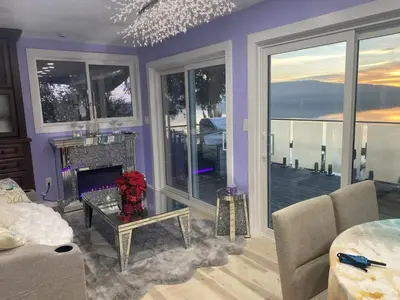 a living room with a fireplace and large windows at Stunning oceanfront home 4br3b sunrise beachcombing near Bamberton Park in Mill Bay