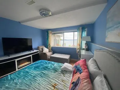 a blue living room with a bed and a tv at Stunning oceanfront home 4br3b sunrise beachcombing near Bamberton Park in Mill Bay
