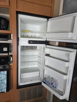 an open refrigerator with water bottles in it at Family RV in a farm in Nanoose Bay