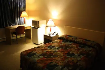 a hotel room with a bed and a desk and a refrigerator at Lamplighter Inn in Three Hills