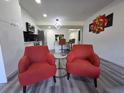 two red chairs and a table in a living room at The Walkout at the Ravine in Edmonton