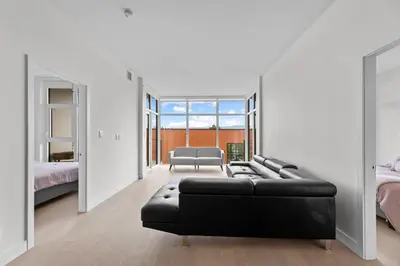 a living room with a black couch and a bed at Gyro Beach Vacations in Kelowna