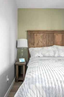a bed with a wooden headboard and a table with a lamp at YYC HiddenGem in Calgary
