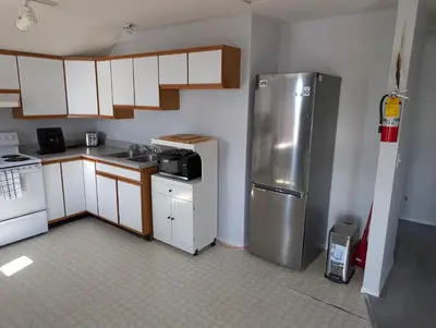 a kitchen with a stainless steel refrigerator and white cabinets at Alert Bay, Spacious Executive Suite with Panoramic Ocean Views in Alert Bay
