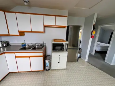 a kitchen with white cabinets and a stainless steel refrigerator at Alert Bay, Spacious Executive Suite with Panoramic Ocean Views in Alert Bay