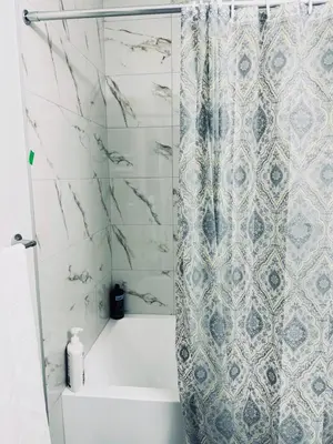 a bathroom with a shower curtain and a tub at Cozy house with 4 Bedrooms 3 Full bath and 1 half bath in Calgary