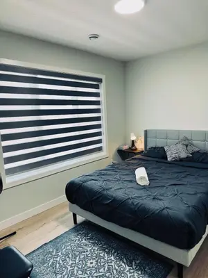 a bedroom with a bed and a large window at Cozy house with 4 Bedrooms 3 Full bath and 1 half bath in Calgary