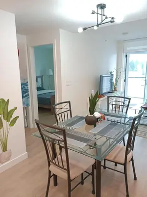a dining room with a glass table and chairs at New condo Great amenities Near Skytrain in Coquitlam