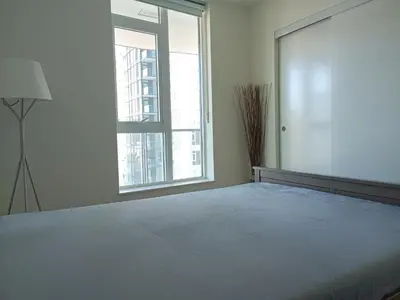 a bedroom with a large bed with a large window at New condo Great amenities Near Skytrain in Coquitlam