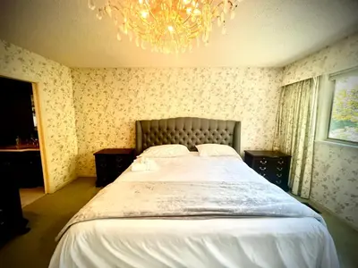 a bedroom with a large bed with a chandelier at Luxury Space close to UBC in Vancouver