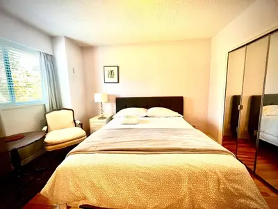 a bedroom with a large bed and a chair at Luxury Space close to UBC in Vancouver