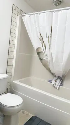 a bathroom with a toilet and a bath tub with a shower curtain at Red Deer Stay- 2BR Private Suite in Red Deer
