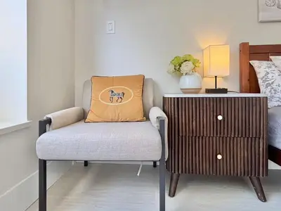 a chair with an orange pillow next to a nightstand at Vancouver Mini Suite in Vancouver