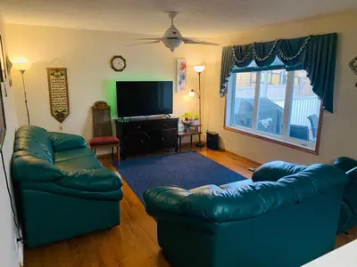 a living room with two couches and a flat screen tv at Master Bedroom with attached bathroom in Airdrie