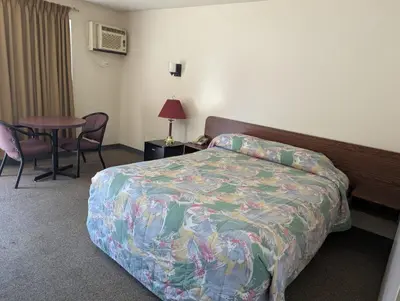a hotel room with a bed and a table with chairs at Algonquin Motor Lodge in Edmonton