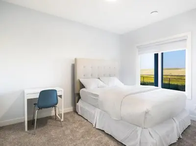 a white bedroom with a bed and a desk and a chair at Olympia Lodge 2 room Apartment in Calgary
