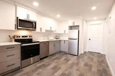a kitchen with white cabinets and stainless steel appliances at Olympia Lodge 2 room Apartment in Calgary
