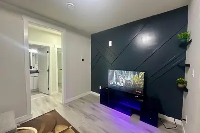 a living room with a flat screen tv on a wall at Cozy 2BR Retreat - 10 Mins to WEM - Free Parking & WiFi in Edmonton
