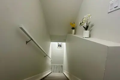 a hallway with a staircase with flowers in a vase at Cozy 2BR Retreat - 10 Mins to WEM - Free Parking & WiFi in Edmonton