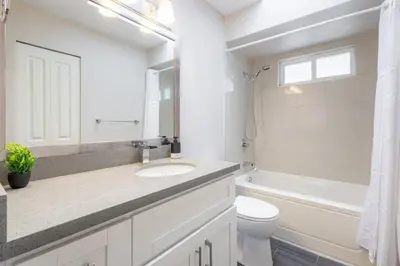 a white bathroom with a sink and a toilet at Soothing Minimalist Escape - Suite with Balcony & Fireplace in Vancouver