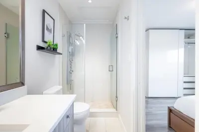 a white bathroom with a toilet and a shower at Soothing Minimalist Escape - Suite with Balcony & Fireplace in Vancouver