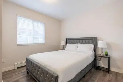 a bedroom with a large bed and a window at Soothing Minimalist Escape - Suite with Balcony & Fireplace in Vancouver