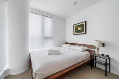 a white bedroom with a bed and a window at Urban Retreat 2BR Condo with Stunning City View in Vancouver