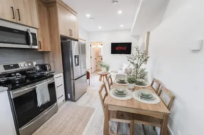 a kitchen with a wooden table with chairs and a stove at Chic Garden Suite Hideaway 2Bedroom Games Room in Edmonton
