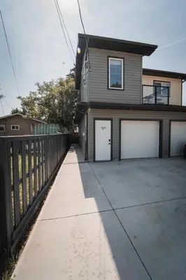 a house with two garage doors and a fence at Chic Garden Suite Hideaway 2Bedroom Games Room in Edmonton