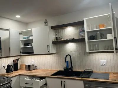 a kitchen with white cabinets and a sink at Cedar & Sage Suite the Cozy Retreat with Full Kitchen in Victoria