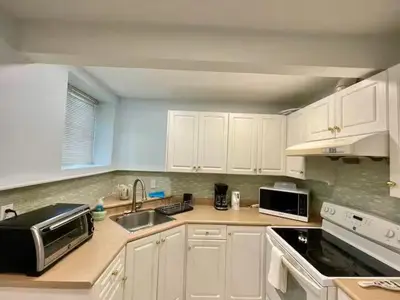 a kitchen with white cabinets and a sink and a microwave at Holiday Home in Coquitlam