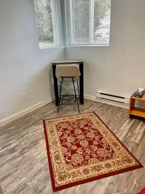 a room with a chair and a rug and a table at Holiday Home in Coquitlam
