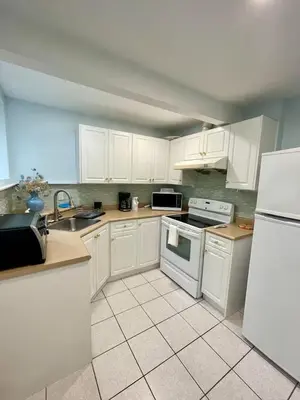 a kitchen with white cabinets and white appliances at Holiday Home in Coquitlam