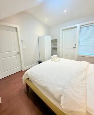 a white bedroom with a large bed and two windows at The Cozy Quad In the Heart of Vancouver in Vancouver
