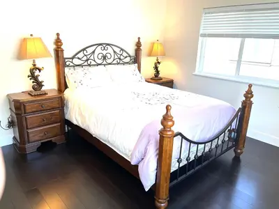 a bedroom with a bed and two night stands at European-American Style Suite in Coquitlam