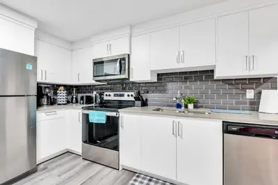 a kitchen with white cabinets and stainless steel appliances at Private, Stylish and Peaceful 2BR Guest Suite in Calgary