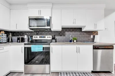 a kitchen with white cabinets and a stove top oven at Private, Stylish and Peaceful 2BR Guest Suite in Calgary