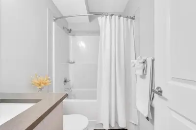 a bathroom with a white shower curtain and a tub at Private, Stylish and Peaceful 2BR Guest Suite in Calgary