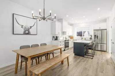 a kitchen and dining room with a wooden table and chairs at King Bed, AC, Fenced Yard, Family Friendly, 5 min South Health Campus in Calgary