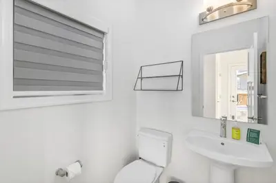 a white bathroom with a toilet and a sink at King Bed, AC, Fenced Yard, Family Friendly, 5 min South Health Campus in Calgary