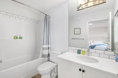 a white bathroom with a sink and a toilet at King Bed, AC, Fenced Yard, Family Friendly, 5 min South Health Campus in Calgary