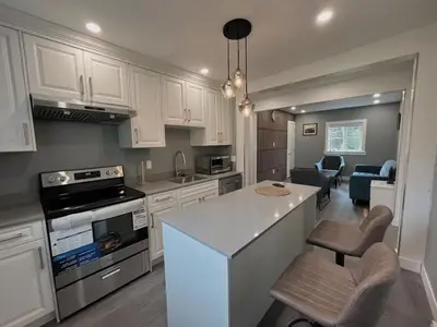 a kitchen with white cabinets and a kitchen island with chairs at Sunshine garden 3 bedrooms2 bathrooms1 living room1 kitchen in Aldergrove