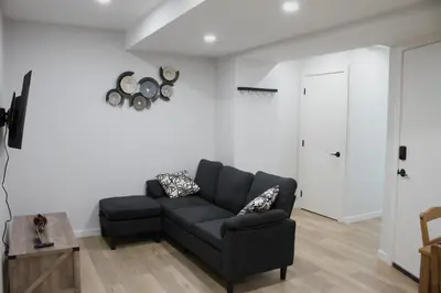 a living room with a black couch and a table at Modern 2 Beds 1 Bath Private Suite, Close to mountains in Calgary